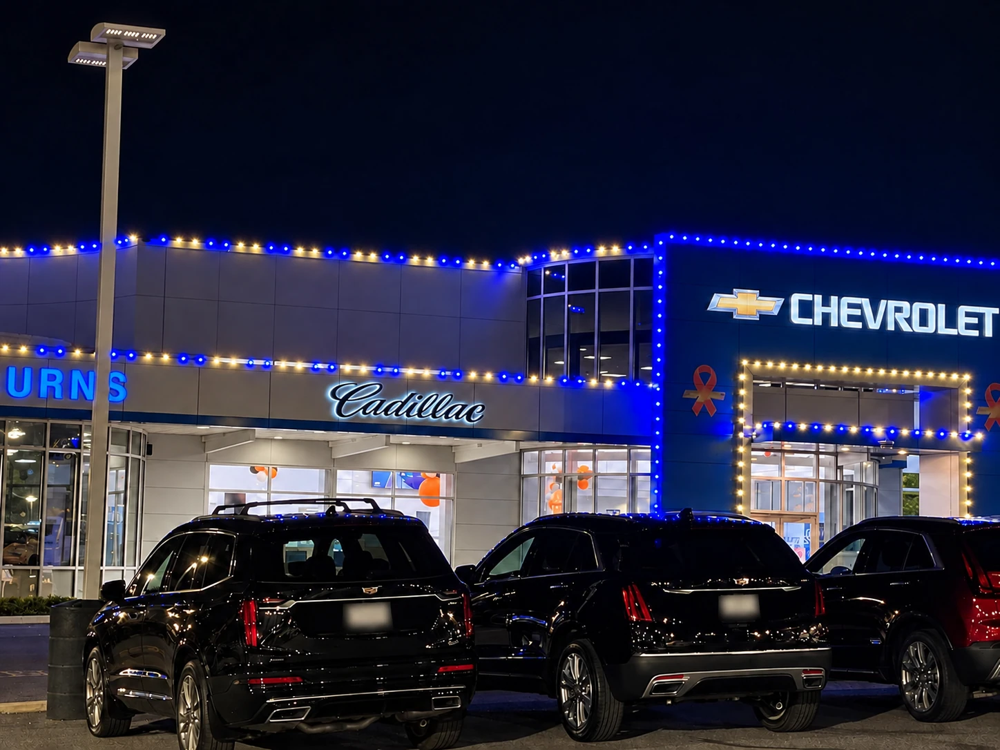 Blue and white holiday lighting across a dealership facade