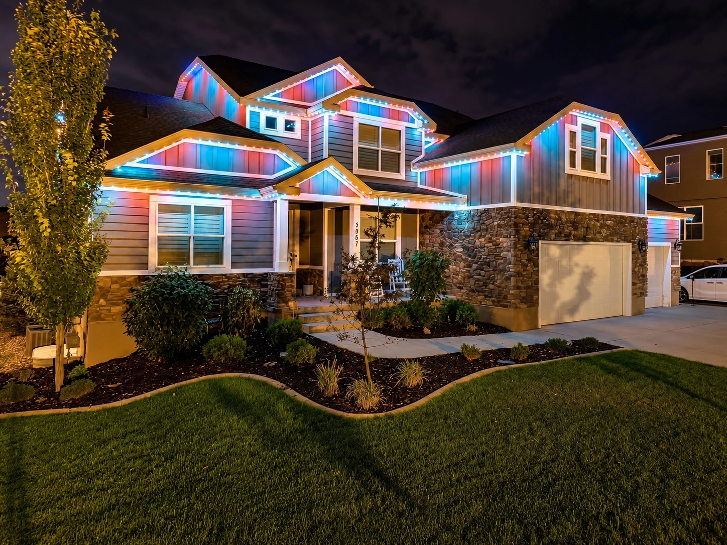 Red, white, and blue permanent lights on a stone home
