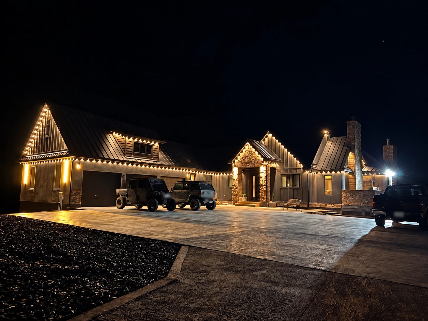 Warm architectural roofline lighting on a dark stone home