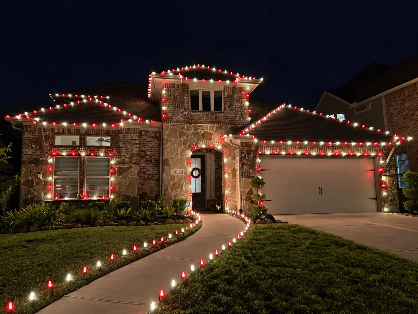 Red and white roofline lights on a stone home