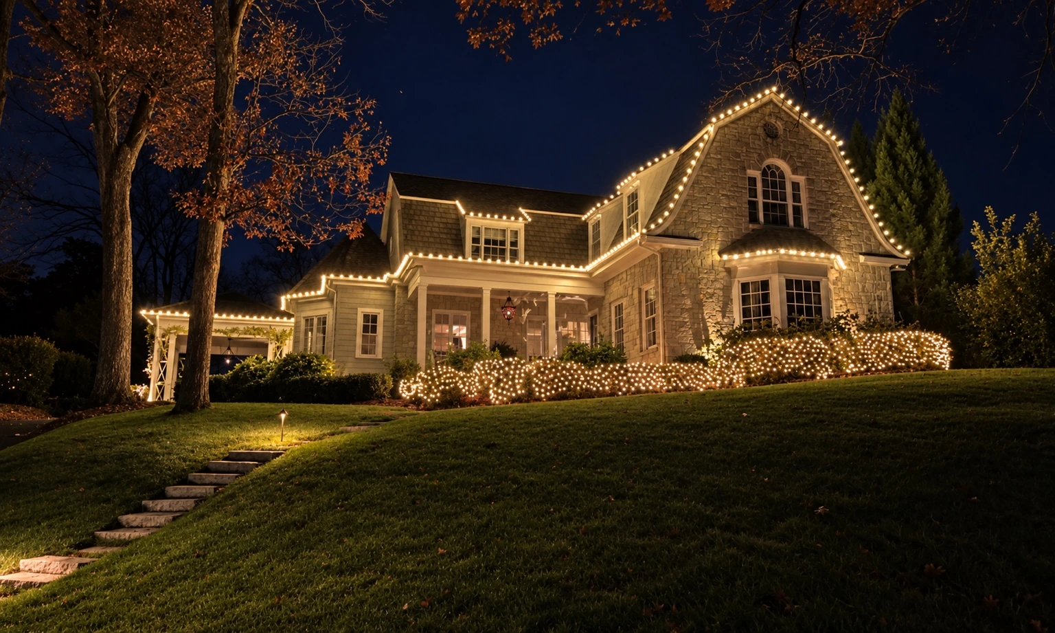 A hillside home with warm roofline and landscape Christmas lights